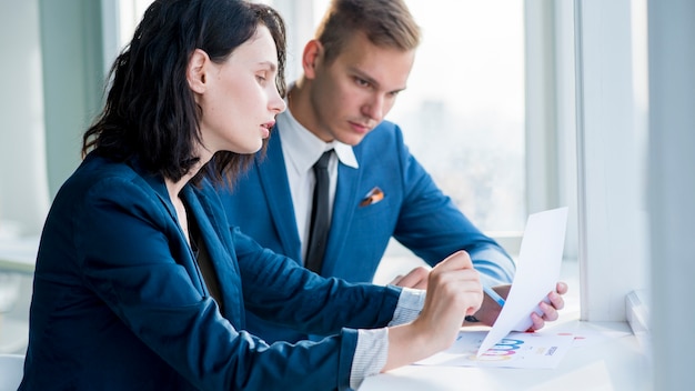 Two businesspeople examining chart at workplace