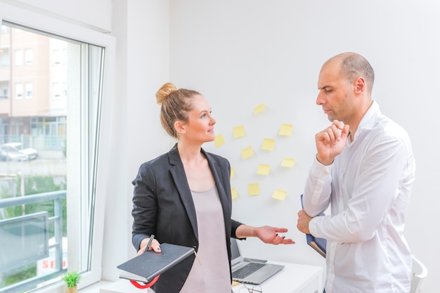 Foto gratuita due persone di affari che hanno discussione in ufficio