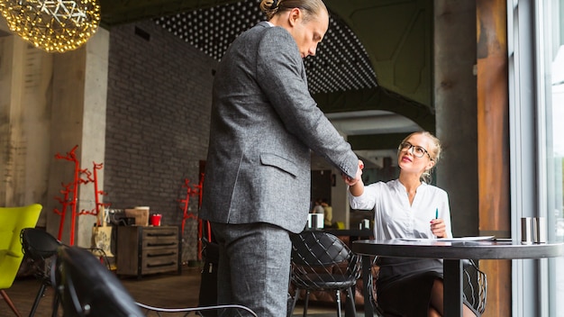 Two businesspeople shaking hands in restaurant