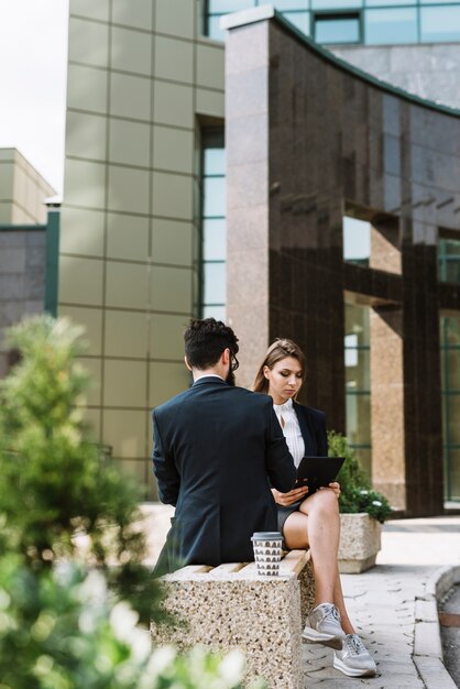 Two businesspeople sitting on bench outside the office building