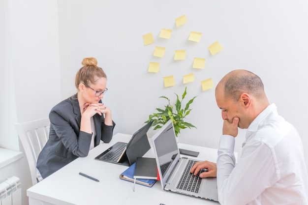 Two businesspeople sitting opposite each other working on laptop