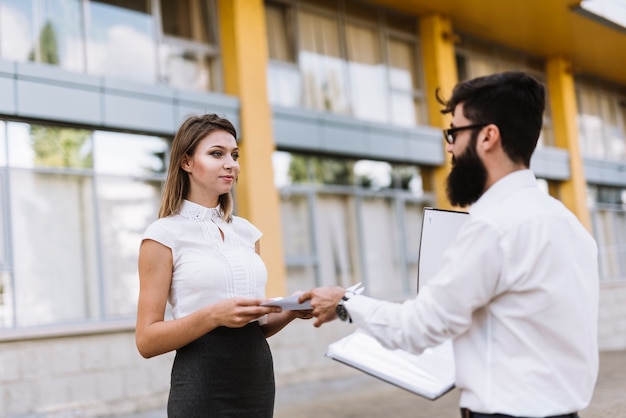 Two businesspeople standing outside the office giving documents