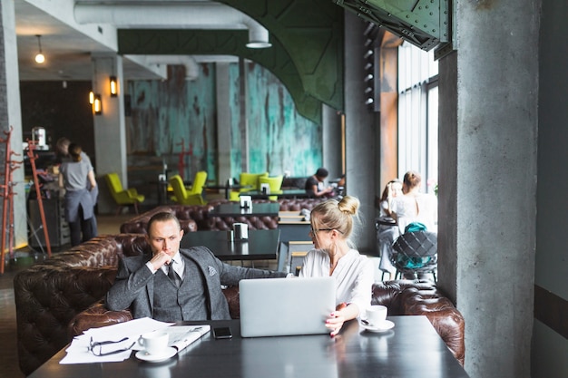 Two businesspeople with laptop sitting in restaurant
