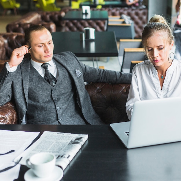 Free photo two businesspeople working on laptop in caf�