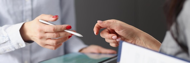 Two businesswoman chatting and holding tablet and documents mobile applications for business