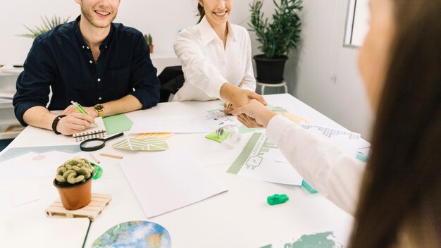 Two businesswoman shaking hands over desk in office