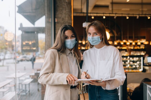 Two businesswomen with their face masks debating different views on work