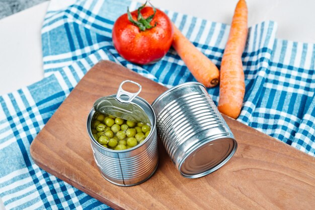 Two cans of boiled green peas, vegetables and tablecloth.