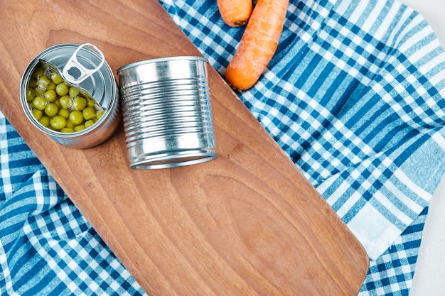 Two cans of boiled green peas, vegetables and tablecloth.
