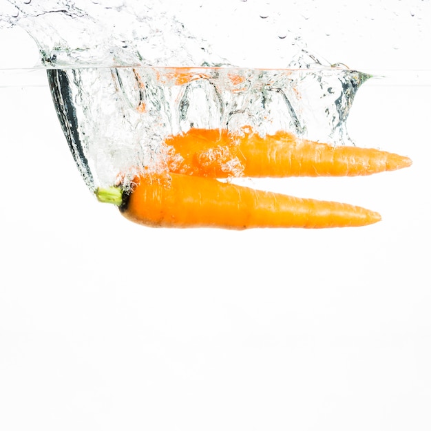 Бесплатное фото Две моркови, плещутся в воде на белом фоне