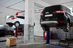 Free photo two cars lifting in maintenance at garage service station