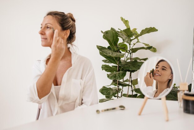 Two caucasian girls of different ages do cosmetic facial procedures in light room. Wellness and self care concept