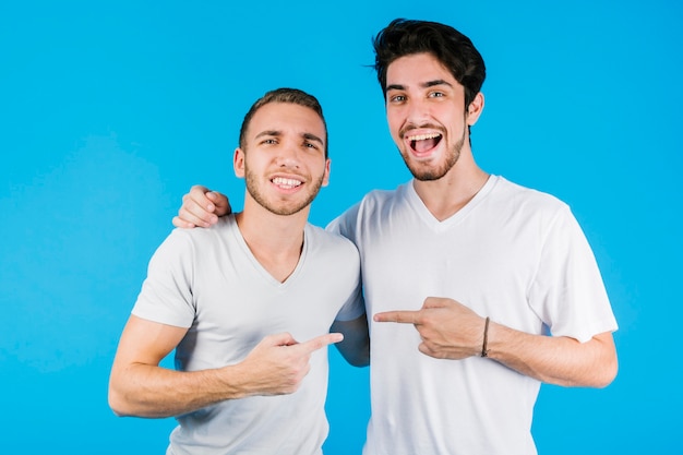 Free photo two cheerful friends pointing at each other