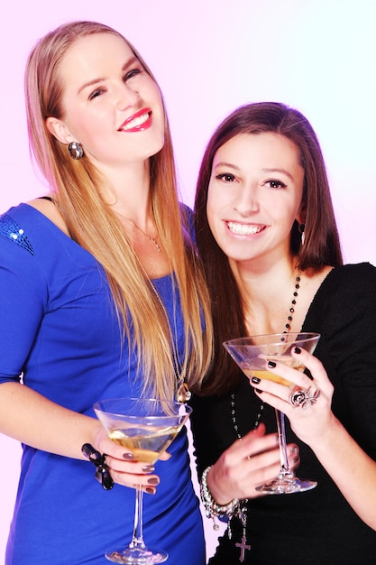 Two cheerful girlfriends with colorful cocktails