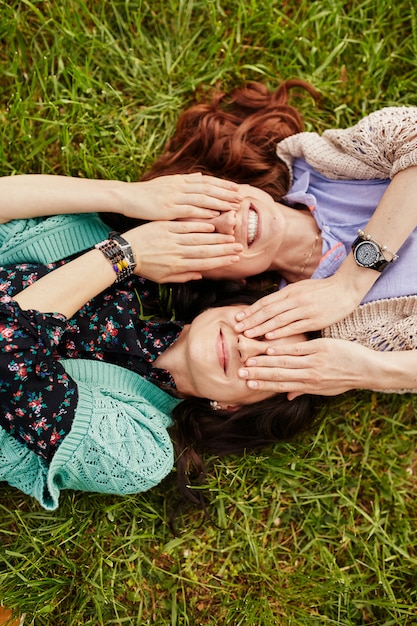 Two cheerful sisters lying on the grass