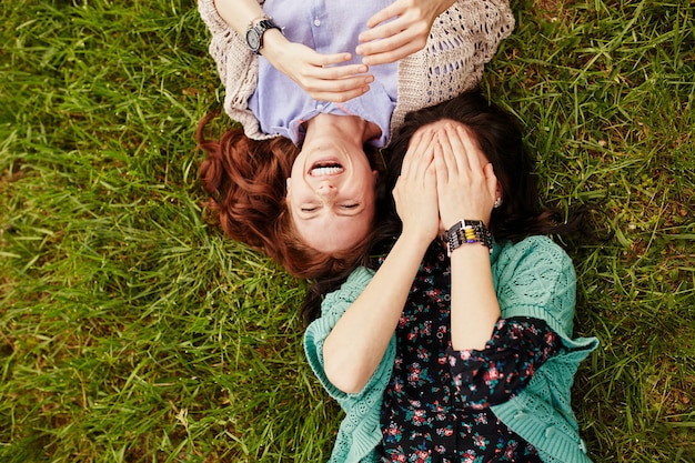 Две веселые сестры лежат на траве