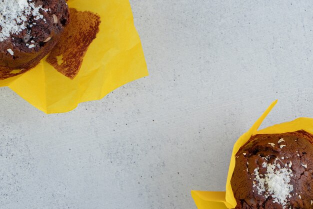 Two chocolate cupcakes on marble background.