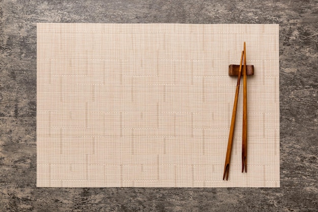セメント​の​背景​に​2​本​の​箸​と​竹​マット​上面図​コピー​スペース