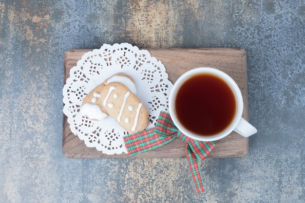 木の板に2つのクリスマスクッキーとお茶。高品質の写真