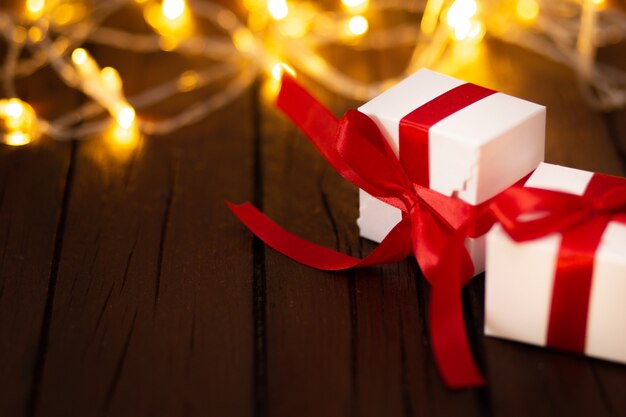 Two Christmas gifts on a wooden table with bokeh lights