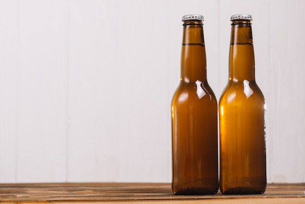 Two closed beer bottles on wooden desk