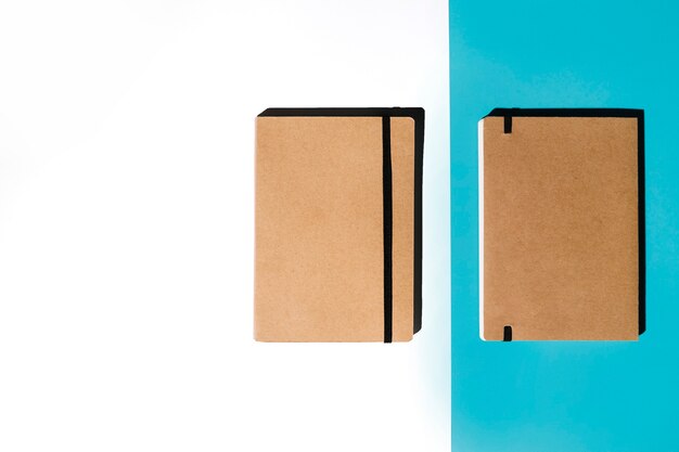 白と青の背景に茶色のカバー付きの2つの閉じたノートブック