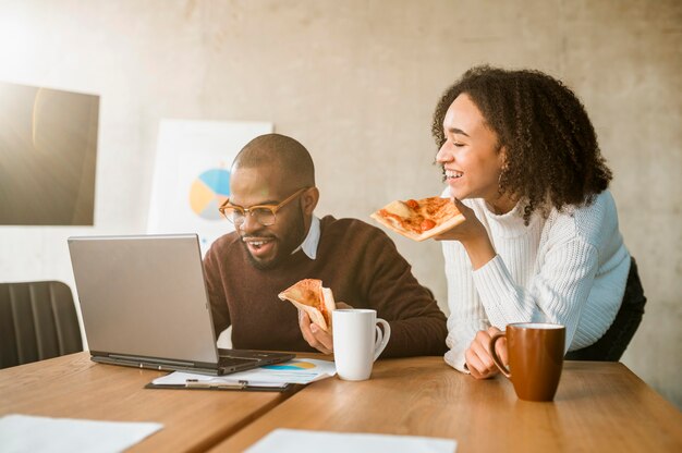 Two colleagues having pizza during an office meeting break