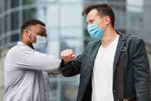 Free photo two colleagues touching elbows outdoors during pandemic