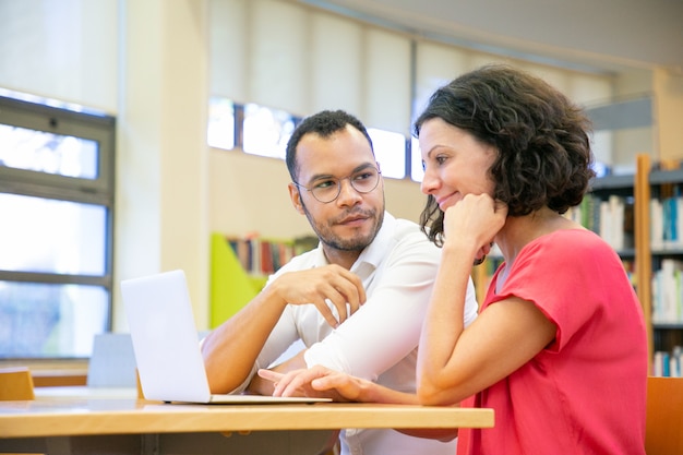 Two colleagues working on presentation in library