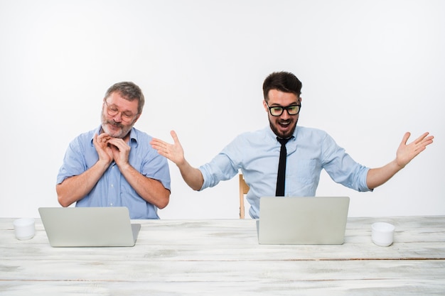 The two colleagues working together at office on white  background. both are looking at the computer screens. Both surprised. concept of positive emotions and good news