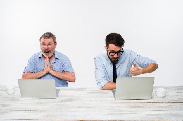 Two colleagues working together at office on white