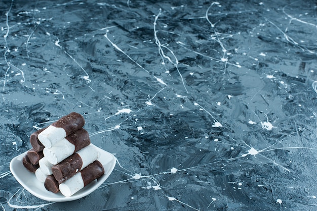 Two-color candies on plate on blue. 