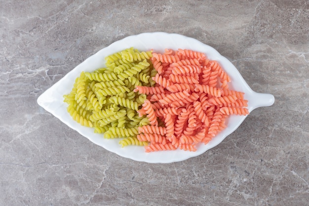 Free photo two-colored fusilli pasta in bowl , on the marble.