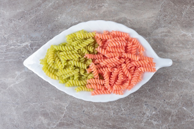Two-colored Fusilli pasta in bowl , on the marble.