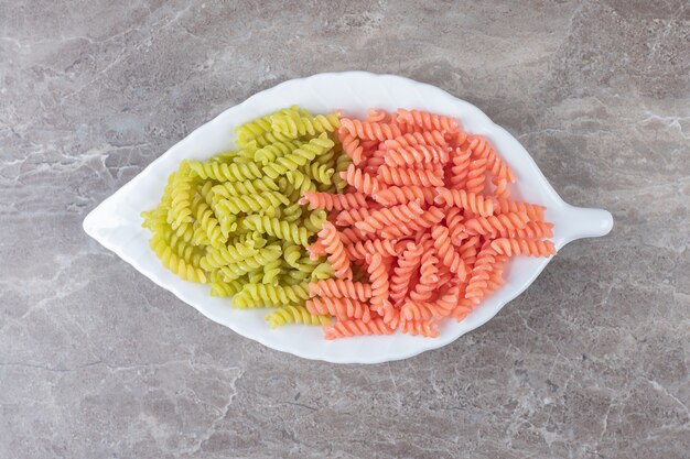 Two-colored Fusilli pasta in bowl , on the marble.