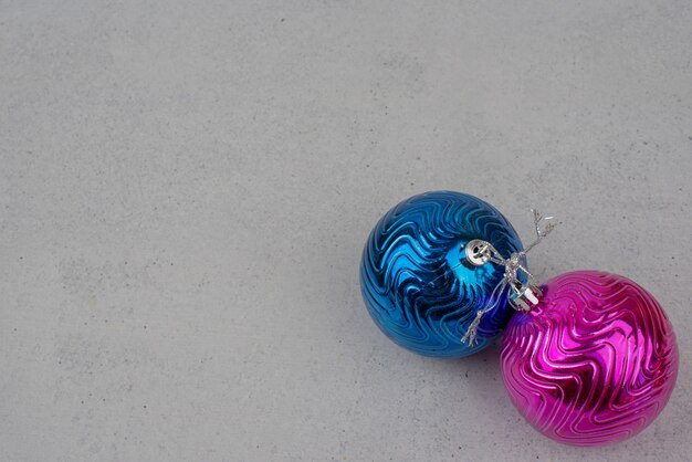 Two colourful Christmas balls on gray wall.