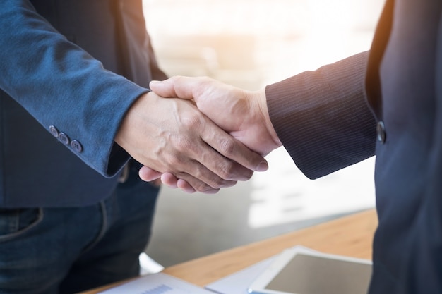 Free photo two confident business man shaking hands during a meeting in the office, success, dealing, greeting and partner concept