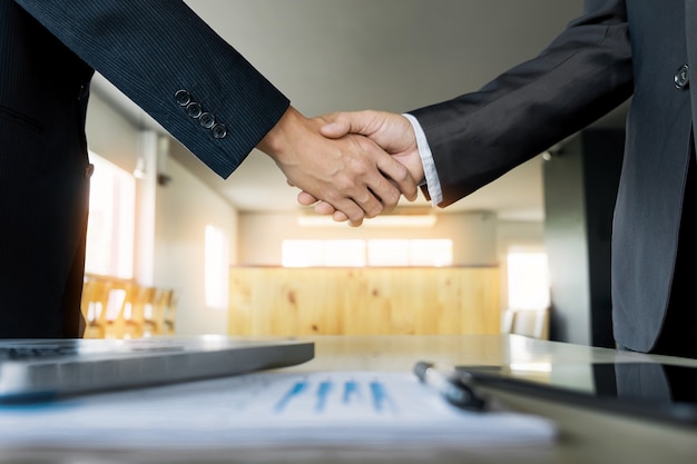 Free photo two confident business man shaking hands during a meeting in the office, success, dealing, greeting and partner concept