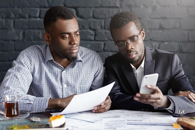 Two confident and serious African-American businessmen focused on paperwork
