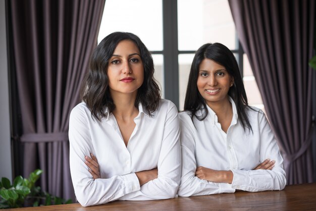 Two content female colleagues at cafe table. 