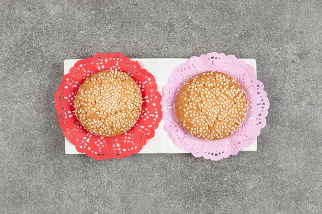 Free photo two cookies with sesame seeds on white saucer