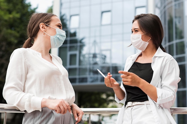 Двое коллег в масках болтают на открытом воздухе во время пандемии