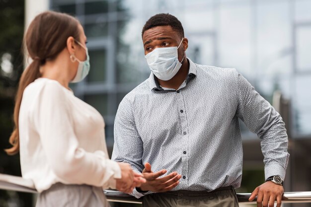 Two coworkers chatting outdoors during pandemic with masks