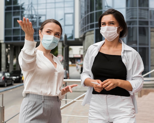 Two coworkers outdoors during pandemic wearing masks