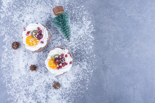 Two creamy pastries with sugar powder on a gray surface