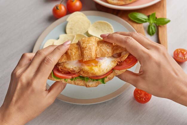 Two croissant sandwiches on wooden table, top view