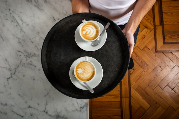 Free photo two cups of coffee with latte art on the tray