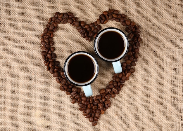 Two cups of espresso in a heart shaped coffee beans.