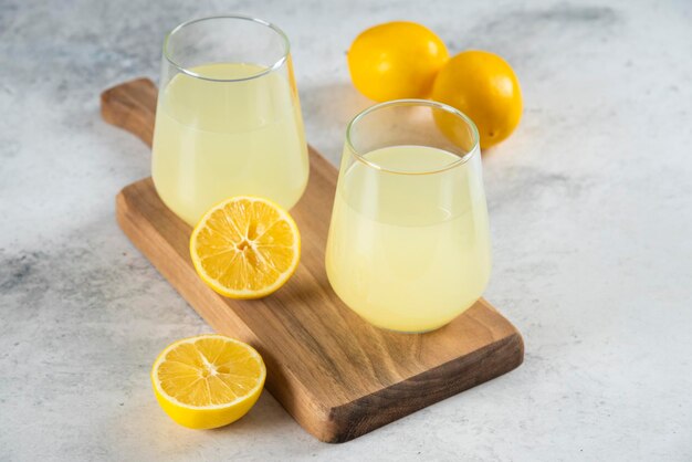 Two cups of fresh lemonade on a wooden board.