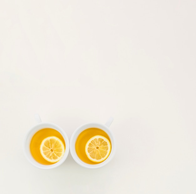 Free photo two cups of green tea with lemon slice on white backdrop